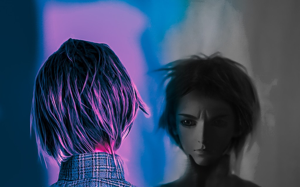 a young man looks at his reflection in his computer monitor